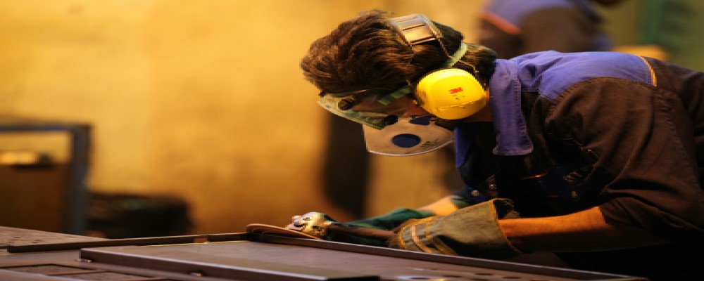 Worker using industrial abrasives with safety gear in a workshop, showcasing Jones and Clark Ltd's range of sanding, grinding, and finishing products in Burton-on-Trent.